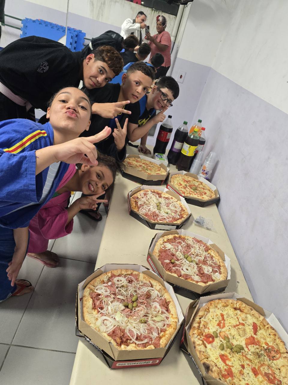 Alunos do Projeto Mão Com Mão reunidos ao redor das pizzas depois do treino