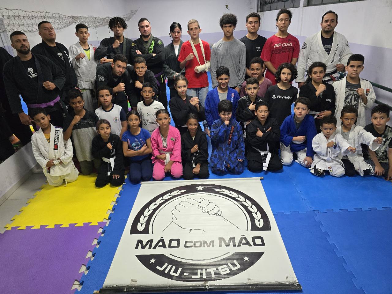 Turma do Projeto Mão com Mão reunida com a bandeira do projeto