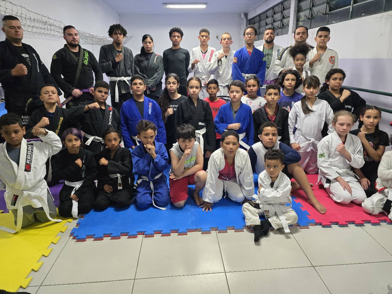 Turma infantil e adulta do Projeto Mão com Mão reunida no tatame